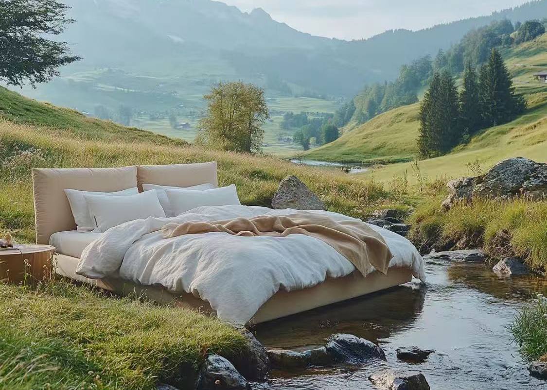 Bed with white duvet and camel throw beside a mountain stream